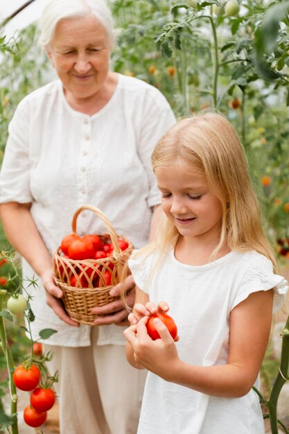 Avó de tiro médio e menina com tomates