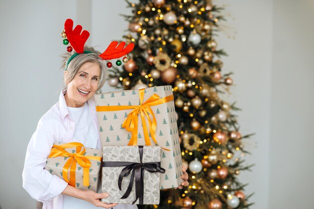 Avó usando chapéu de natal de veado presentes de natal nas mãos