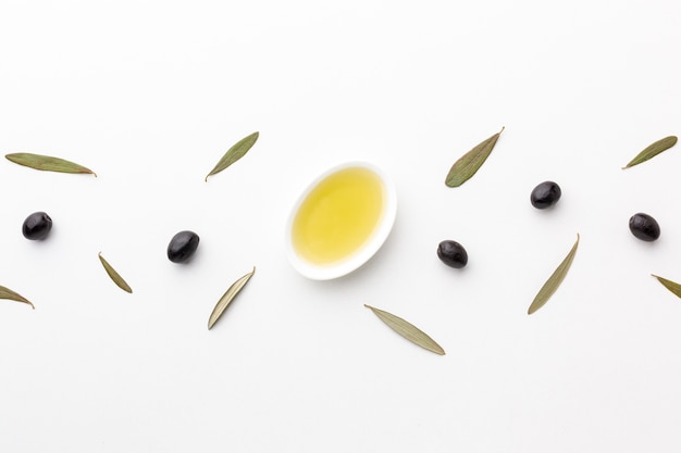 Azeite de oliva liso em pires com folhas e azeitonas pretas