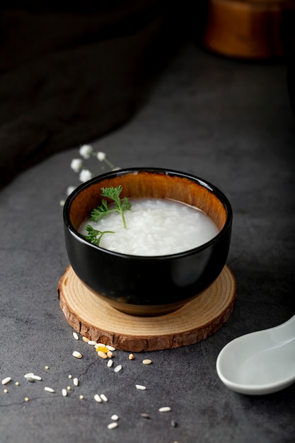 Bacia preta com sopa de arroz em um suporte de madeira