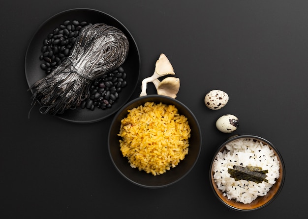 Bacias escuras com macarrão e arroz em um fundo escuro