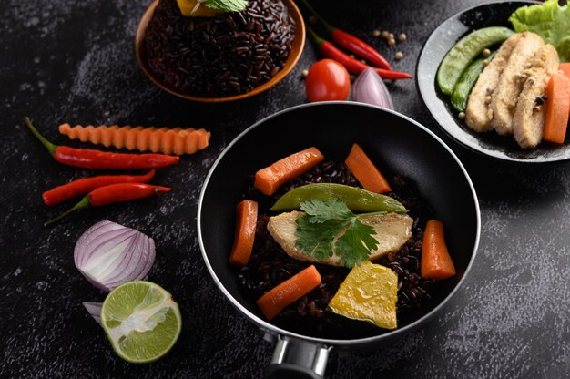 Bagas de arroz roxo cozidas com peito de frango grelhado. Folhas de abóbora, cenoura e hortelã em frigideiras.