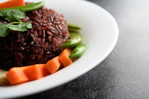 Bagas de arroz roxo cozidas com peito de frango grelhado. Folhas de abóbora, cenoura e hortelã em um prato, comida limpa.