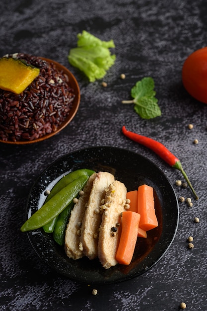 Bagas de arroz roxo cozidas com peito de frango grelhado. Folhas de abóbora, cenoura e hortelã em um prato, comida limpa.