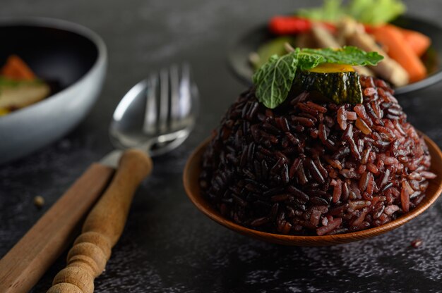 Bagas de arroz roxo cozidas com peito de frango grelhado Folhas de cenoura e abóbora As folhas de hortelã no prato e a colher, garfo, comida limpa.