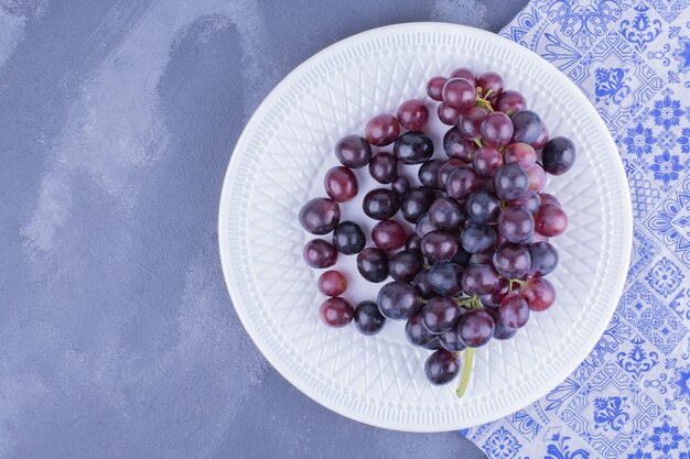 Bagas de uva vermelha em um prato branco.