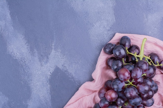 Foto grátis bagas de uva vermelha isoladas na mesa azul.