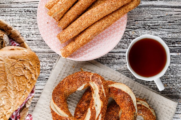 Bagel turco com uma xícara de chá e pão na superfície de madeira, vista superior.