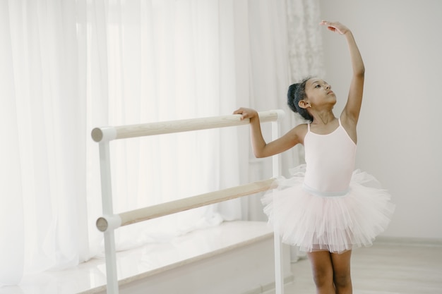 Foto grátis bailarina bonitinha em traje de balé rosa. criança com sapatilhas de ponta está dançando na sala. criança na aula de dança.