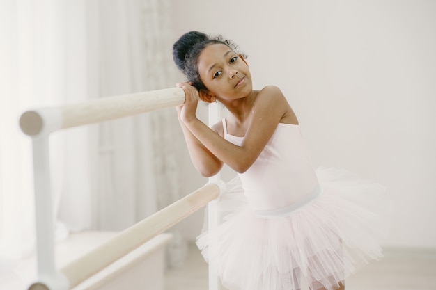 Bailarina bonitinha em traje de balé rosa. criança com sapatilhas de ponta está dançando na sala. criança na aula de dança.