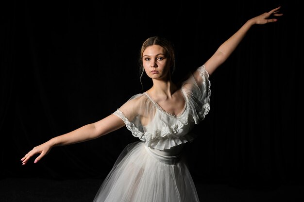 Bailarina com vestido de tutu posando com braços abertos