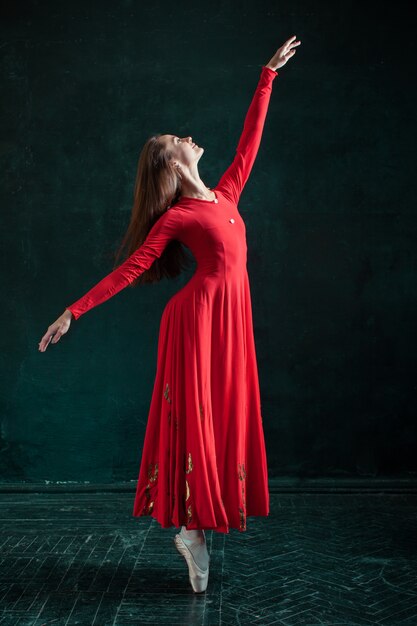 Bailarina posando em sapatilhas no pavilhão de madeira preto