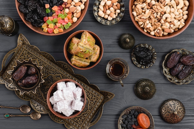 Baklava caseiro de delícia turca; datas; frutas secas e nozes na tigela metálica e barro sobre a mesa