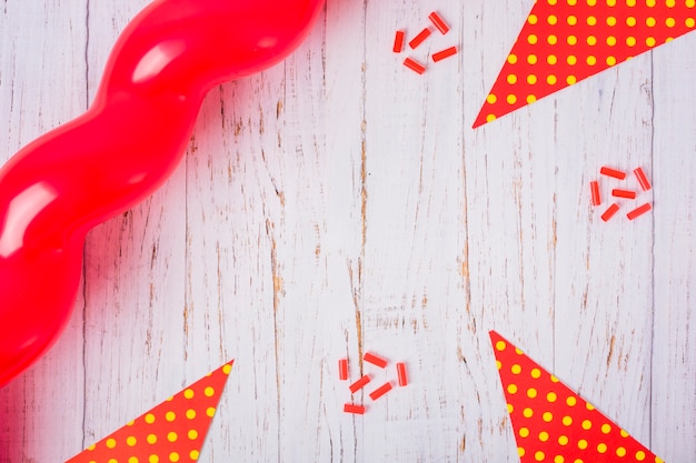 Balão vermelho, papel triangular e doces na mesa de madeira