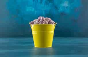 Foto grátis balde de doces pipoca roxos crocantes sobre fundo azul. foto de alta qualidade