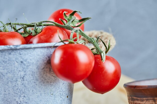 Balde de tomates vermelhos suculentos na mesa de madeira.