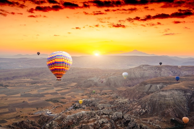 Balões de ar quente flutuando no céu laranja ao pôr do sol na capadócia, na turquia