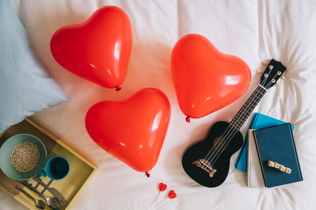 Balões de coração e ukulele na cama