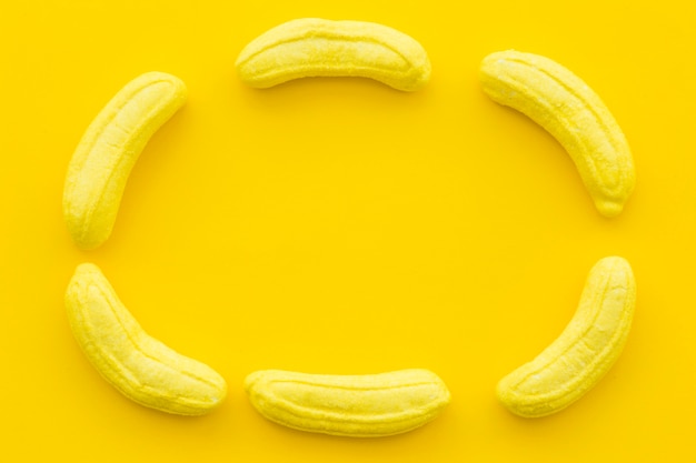 Foto grátis banana em forma de doces formando moldura em fundo amarelo