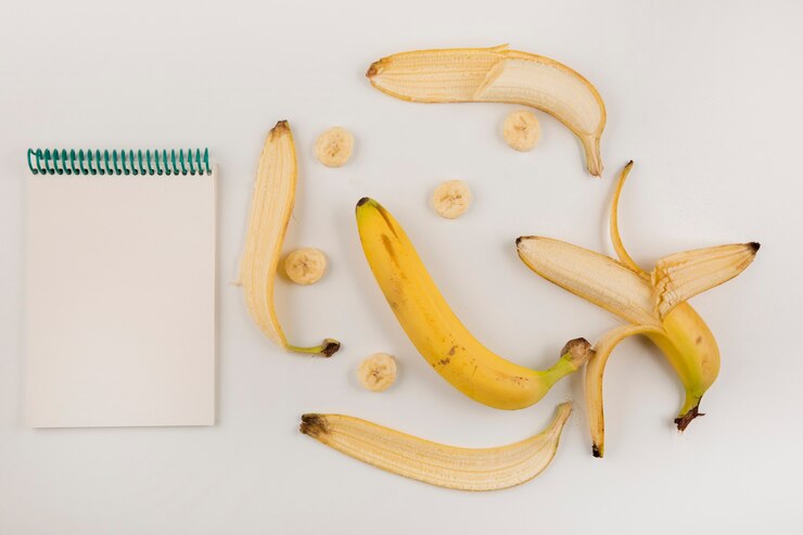 Foto grátis bananas descascadas e fatiadas em fundo branco com um livro de recibos de lado