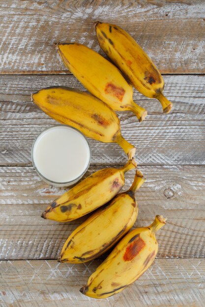 Bananas maduras com vista superior do leite em uma madeira