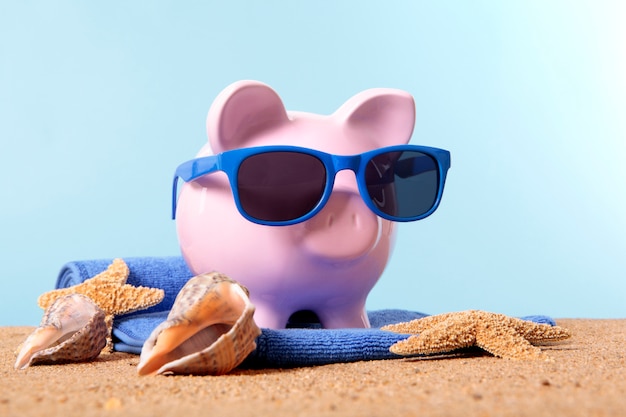 Foto grátis banco piggy em uma praia com óculos de sol