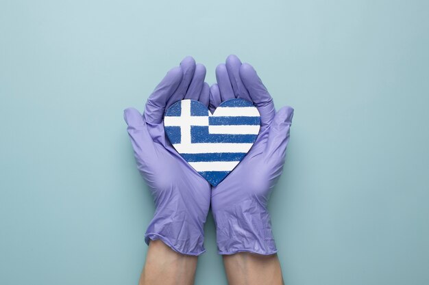 Bandeira da grécia em forma de coração realizada nas mãos