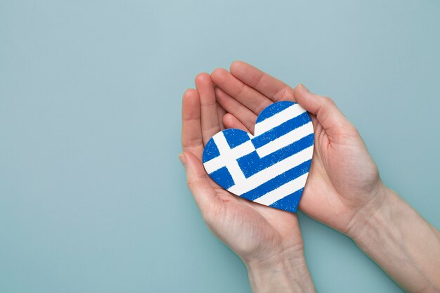 Bandeira da grécia em forma de coração realizada nas mãos