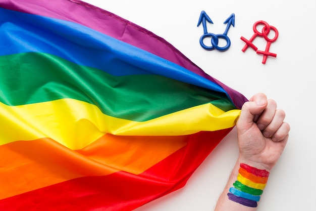 Foto grátis bandeira do orgulho do arco-íris com mão e símbolos