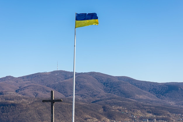 Bandeira ucraniana e cruz no fundo das montanhas