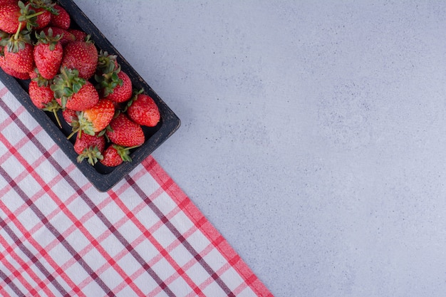 Bandeja de morango alinhada na borda da toalha de mesa sobre fundo de mármore. Foto de alta qualidade