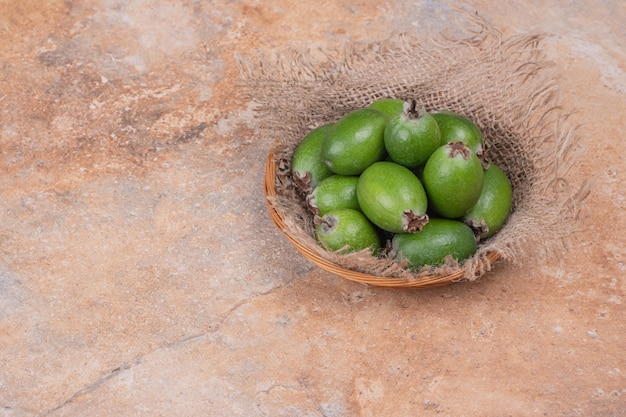 Bando de feijoas em uma tigela em fundo laranja.