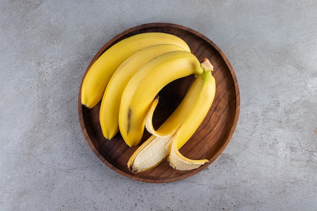 Bando de suculenta banana amarela colocada sobre uma mesa de pedra.