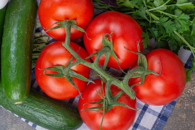 Bando de tomates, verdes e pepinos na toalha de mesa.