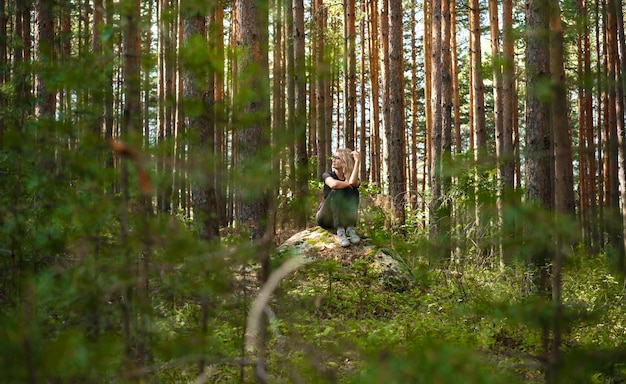 Foto grátis banhos de floresta restaurando a saúde e a força no fim de semana de uma mulher adulta sentada em uma saliência rochosa