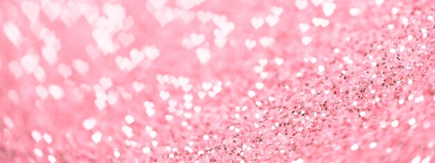 Banner da web de dia dos namorados. bokeh romântico de corações brilhantes em fundo de brilho rosa pastel. cenário de férias turva.
