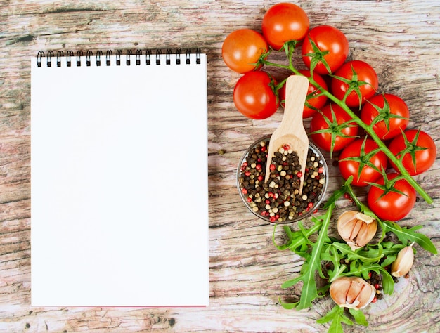 Banner de comida horizontal com tomate cereja, rúcula, alho, pimenta e notebook.