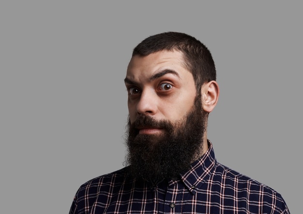 Barba comprida e bigode grande com sobrancelha levantada. homem brutal e sério atirou isolado em fundo cinza neutro.