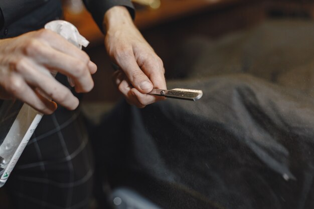 Barbearia. Close de barbeiro segurando navalha para raspar a barba