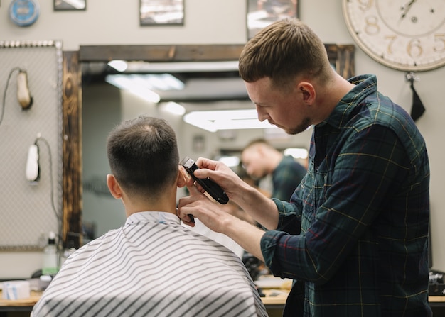 Foto grátis barbeiro dando um corte de cabelo a um cliente