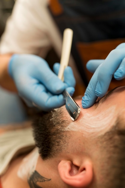 Foto grátis barbeiro fazendo a barba e contornando a barba de um cliente