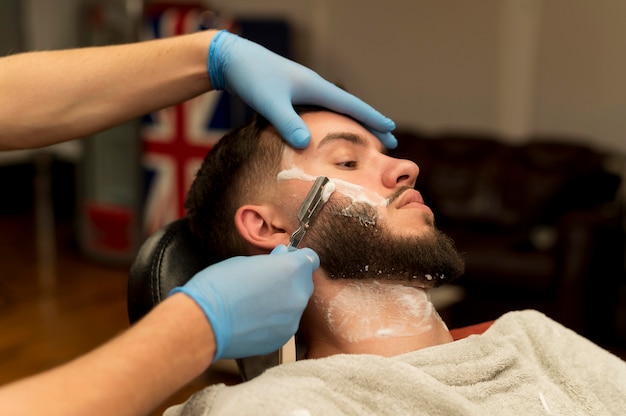 Barbeiro fazendo a barba e contornando a barba de um cliente