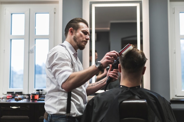 Barbeiro penteando e secando o cabelo do cliente anônimo