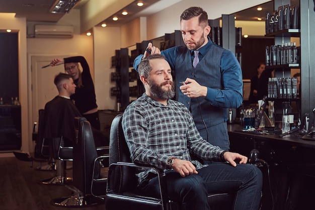 Barbeiro profissional trabalhando com um cliente em um salão de cabeleireiro.