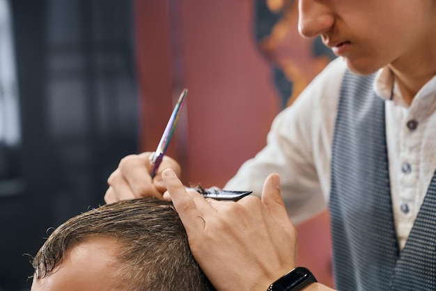 Barbeiro usando tesoura e pente para cortar o cabelo do cliente