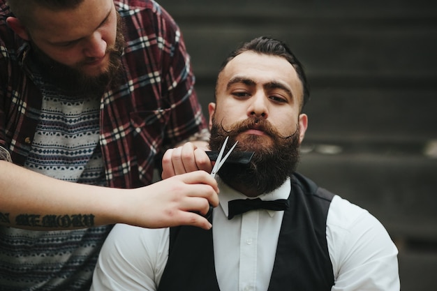 Foto grátis barber faz a barba de um homem barbudo em um ambiente vintage