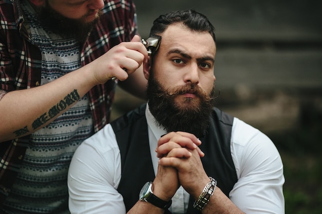 Foto grátis barber faz a barba de um homem barbudo em um ambiente vintage