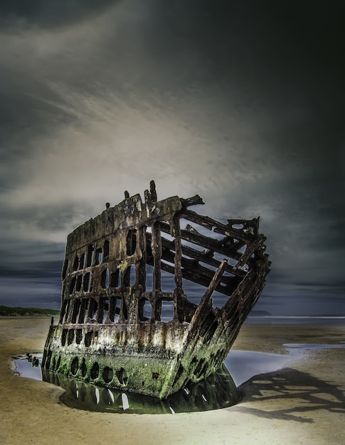 Barco abandonado na praia sob as nuvens de tirar o fôlego