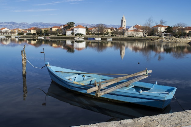 Barco azul amarrado ao longo do cais em uma vila