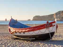 Foto grátis barco de pesca na praia da nazaré em portugal durante o dia